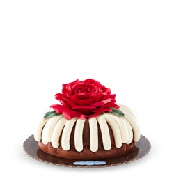 10 in bundt cake with signature frosting and topped with red rose flower.