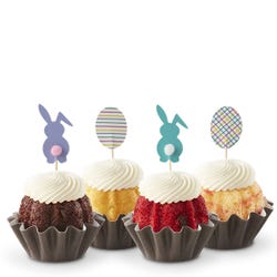 Mini Bundt cakes, each topped with a unique Easter-themed topper: two bunnies and two patterned eggs. 