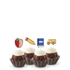 Chocolate Chocolate Chip flavored mini Bundt cakes (Bundtinis®) topped with creamy white frosting, accompanied by school-themed toppers: a sliced apple, a pencil, a notebook, and a yellow school bus.