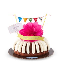 A bundt cake with a banner that says Happy Birthday, with party pennants with various dotted and lined designs. A card reads Cele'bundt'ing YOU!.