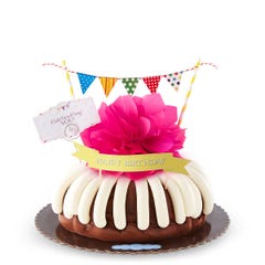 A bundt cake with a banner that says Happy Birthday, with party pennants with various dotted and lined designs. A card reads Cele'bundt'ing YOU!.