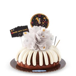 A bundt cake with a celebratory bow in the center with gold and silver stars. It contains a countdown clock topper and a card that reads Hello New Year.