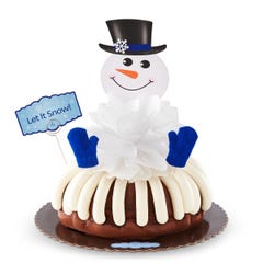 A decorated bundt cake with a snowman with a carrot nose and 2 knit mittens. A card is on the cake that says Let It Snow!.