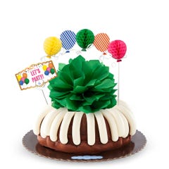A party-themed bundt cake with colorful 3D balloons. The cake has a card that reads LET'S PARTY. 