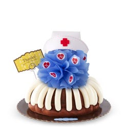 A cake with frosting and topped with a blue bow with heartbeat stickers and a nurse hat at the top. A card reads Thanks! You take the cake.