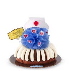 A cake with frosting and topped with a blue bow with heartbeat stickers and a nurse hat at the top. A card reads Thanks! You take the cake.
