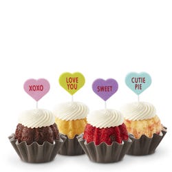 Mini Bundt cakes with white frosting, topped with conversation hearts in pink, lime, lavender, and light teal, displaying messages: XOXO, LOVE YOU, SWEET, and CUTIE PIE.
