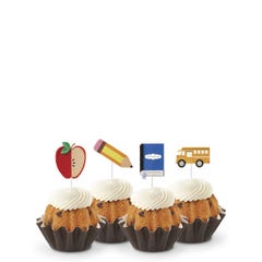 Gluten-Free Chocolate Chip Cookie flavored mini Bundt cakes (Bundtinis®) topped with creamy white frosting, accompanied by school-themed toppers: a sliced apple, a pencil, a notebook, and a yellow school bus.
