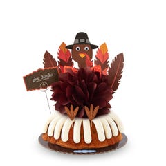 A large Gluten Free Chocolate Chip Cookie bundt cake with a chocolate colored bow in the center and a whimsical turkey cutout with 5 Gratitude Feathers. 