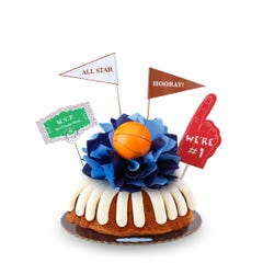 A Gluten-Free Chocolate Chip Cookie bundt cake, decorated with a mini basketball on top of a bow with different shades of blue in the center of the cake.