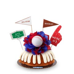 A Gluten-Free Chocolate Chip Cookie bundt cake, decorated with a baseball on top of a purple and white bow in the center of the cake.