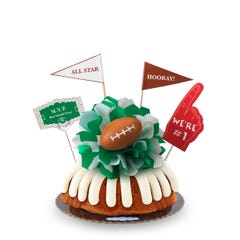 A Gluten-Free Chocolate Chip Cookie bundt cake, decorated with a mini football on top of a green and white bow in the center of the cake.