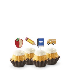 Lemon flavored mini Bundt cakes (Bundtinis®) topped with creamy white frosting, accompanied by school-themed toppers: a sliced apple, a pencil, a notebook, and a yellow school bus.