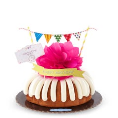 A bundt cake with a banner that says Happy Birthday, with party pennants with various dotted and lined designs. A card reads Cele'bundt'ing YOU!.