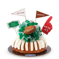 A Lemon bundt cake, decorated with a mini football on top of a green and white bow in the center of the cake.