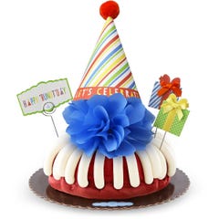 A bundt cake with frosting topped with a party hat that says Let's Celebrate. Two wrapped gift boxes are on the sides along with a card that reads Happy 'Bundt'day.