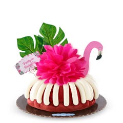 A Red Velvet bundt cake decorated with a pink flamingo with tropical leaves. It also includes a card that reads Party in Paradise. 