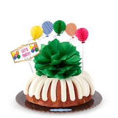 A party-themed bundt cake with colorful 3D balloons. The cake has a card that reads LET'S PARTY. 