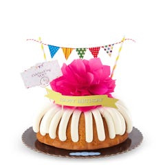 A bundt cake with a banner that says Happy Birthday, with party pennants with various dotted and lined designs. A card reads Cele'bundt'ing YOU!.