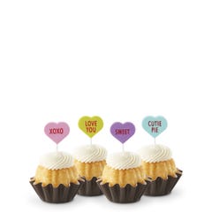 Mini Bundt cakes with white frosting, topped with conversation hearts in pink, lime, lavender, and light teal, displaying messages: XOXO, LOVE YOU, SWEET, and CUTIE PIE.