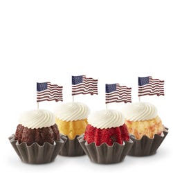 Mini Bundt cakes (Bundtinis®) in a row with creamy white frosting. Each Bundtini is topped with a small American flag.