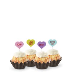 Mini Bundt cakes with white frosting, topped with conversation hearts in pink, lime, lavender, and light teal, displaying messages: XOXO, LOVE YOU, SWEET, and CUTIE PIE.