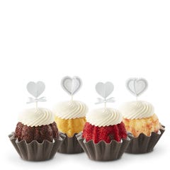Four mini Bundt cakes each adorned with a delicate white heart topper, presented in a row showcasing a variety of cake flavors.