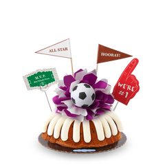 A Gluten-Free Chocolate Chip Cookie bundt cake, decorated with a mini soccer ball on top of a purple and white bow in the center of the cake.
